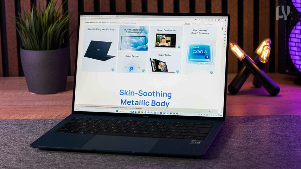 A sleek silver Huawei MateBook X Pro laptop open on a desk, displaying a vibrant image, with a cup of coffee and a notebook beside it - Forever Yena Newspaper